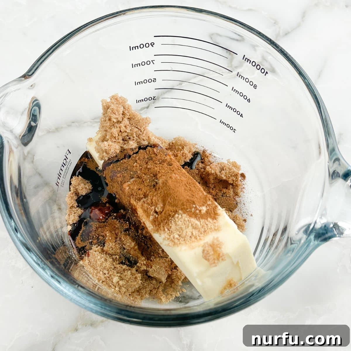 Gingerbread Holiday Crunch 4 A microwave-safe bowl filled with melted butter, rich brown sugar, and dark molasses, forming the base for the gingerbread glaze.