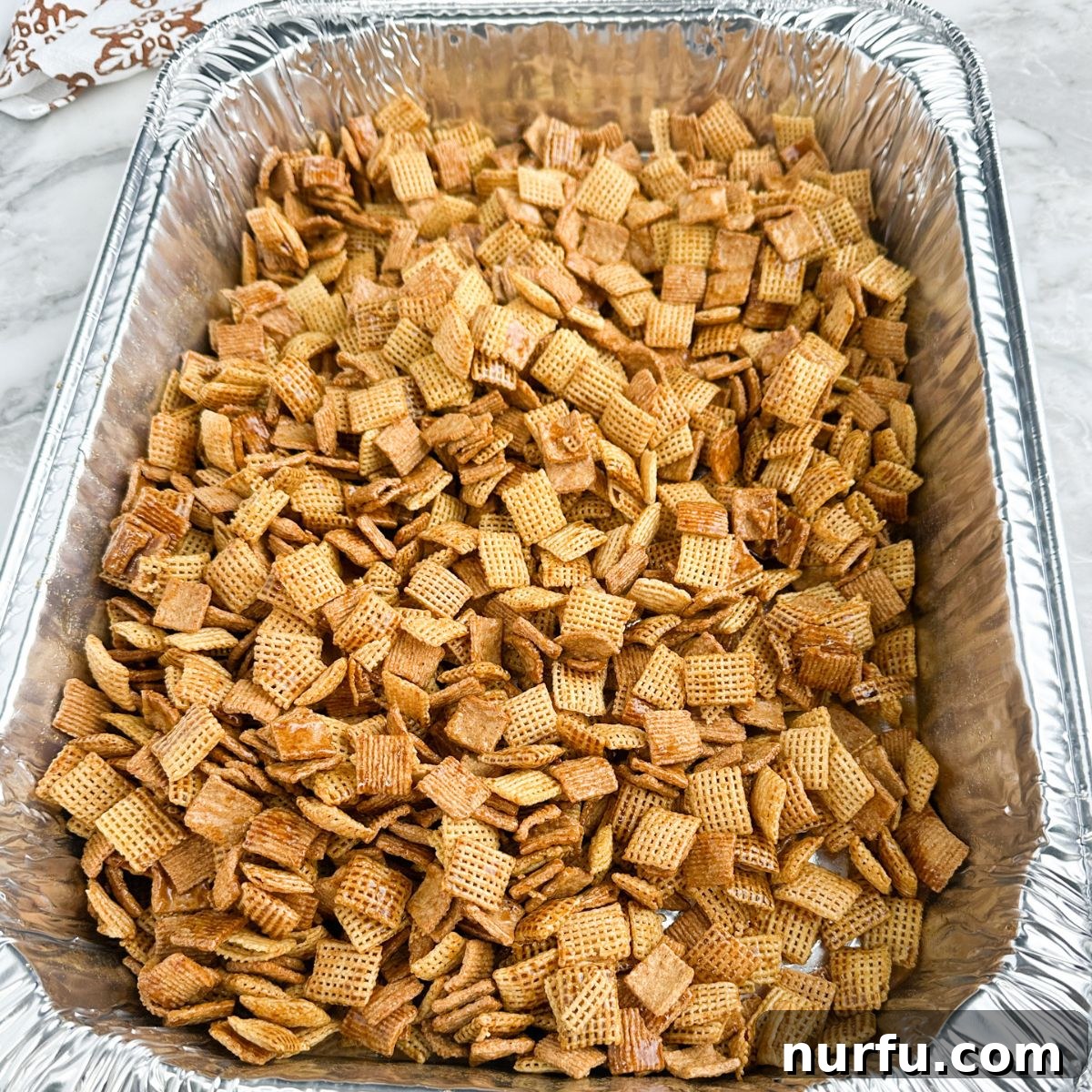 Gingerbread Holiday Crunch 6 A baking pan filled with the golden-brown Gingerbread Chex Mix, freshly baked and perfectly crisp, stirring halfway through baking for even results.