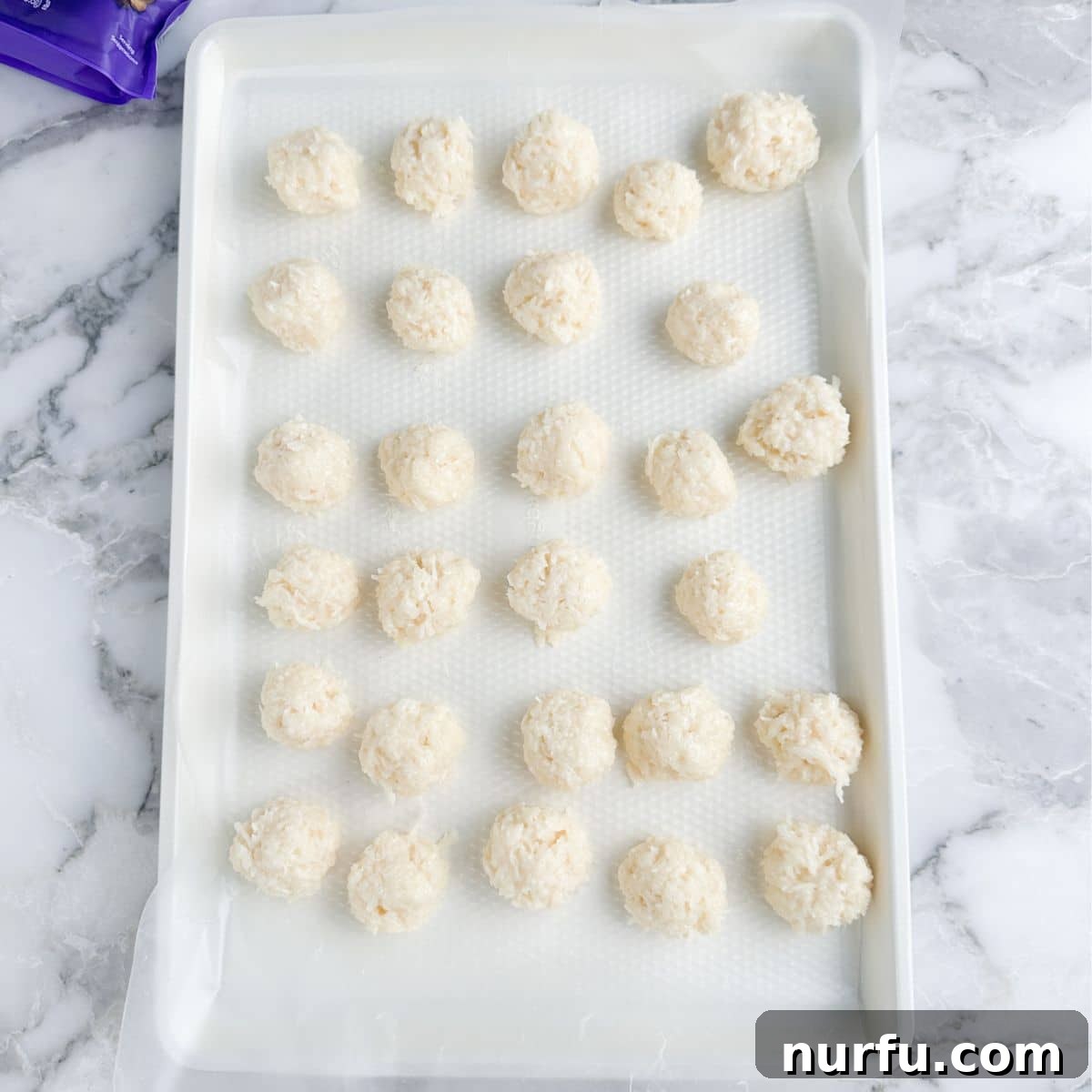 Coconut Chocolate Dream Bites 6 A baking pan lined with wax paper, holding several perfectly formed coconut balls, ready for chilling.