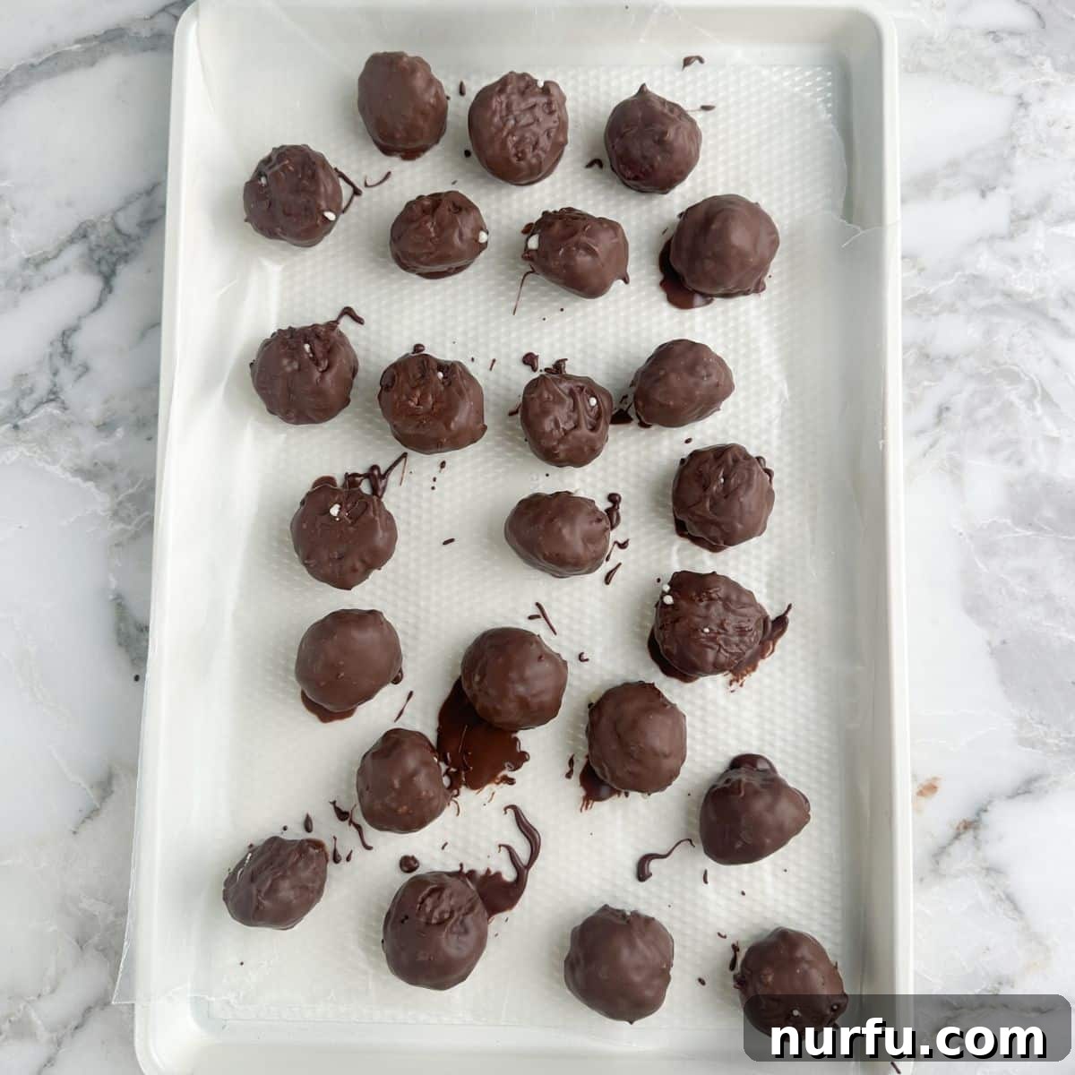 Coconut Chocolate Dream Bites 8 A baking pan filled with freshly dipped chocolate coconut balls, arranged neatly, with the chocolate still setting.