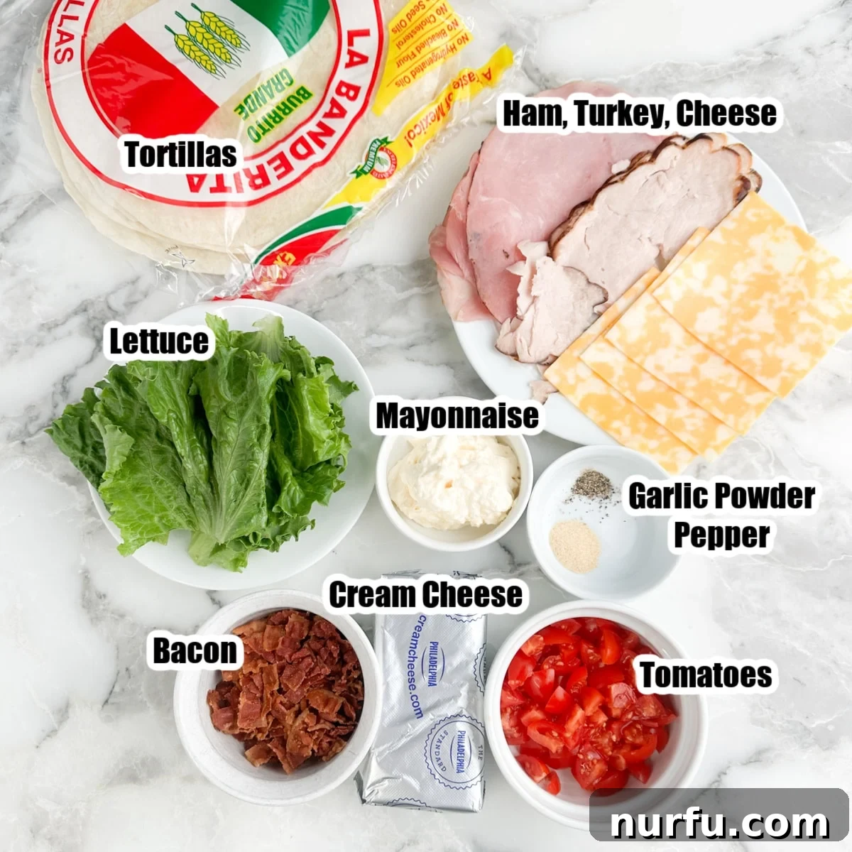 Clubhouse Pinwheel Bites 3 A vibrant flat lay showcasing all the ingredients for club sandwich pinwheels: large tortillas, softened cream cheese, mayonnaise, various deli meats (ham, turkey), sliced cheese, crispy bacon, fresh tomatoes, and crisp lettuce.
