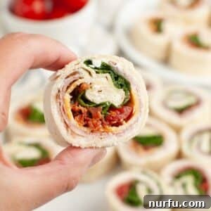 Hand holding a club sandwich pinwheel.