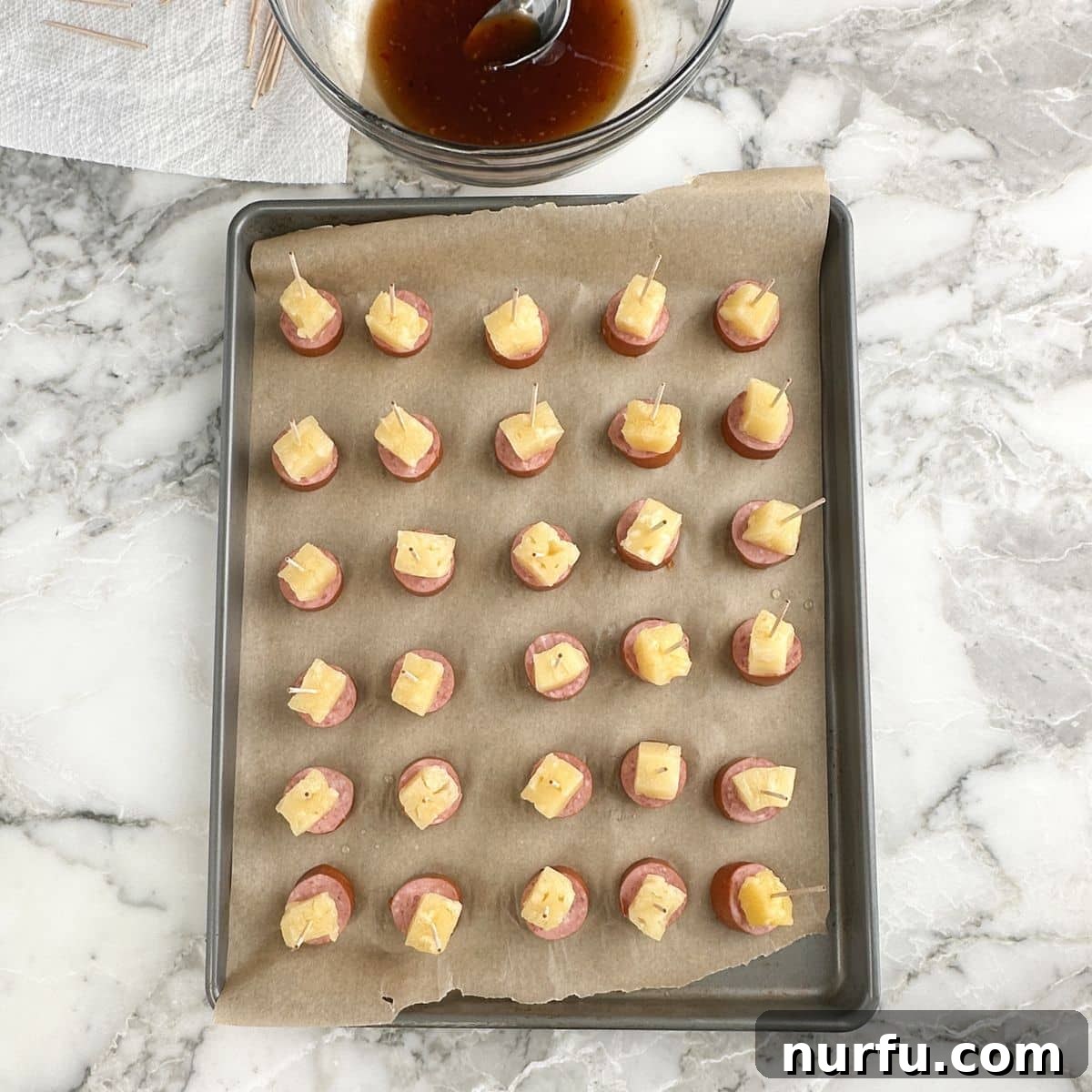 Golden Pineapple Kielbasa Poppers 6 Baking sheet with pineapple kielbasa bites, glazed and ready for the oven.