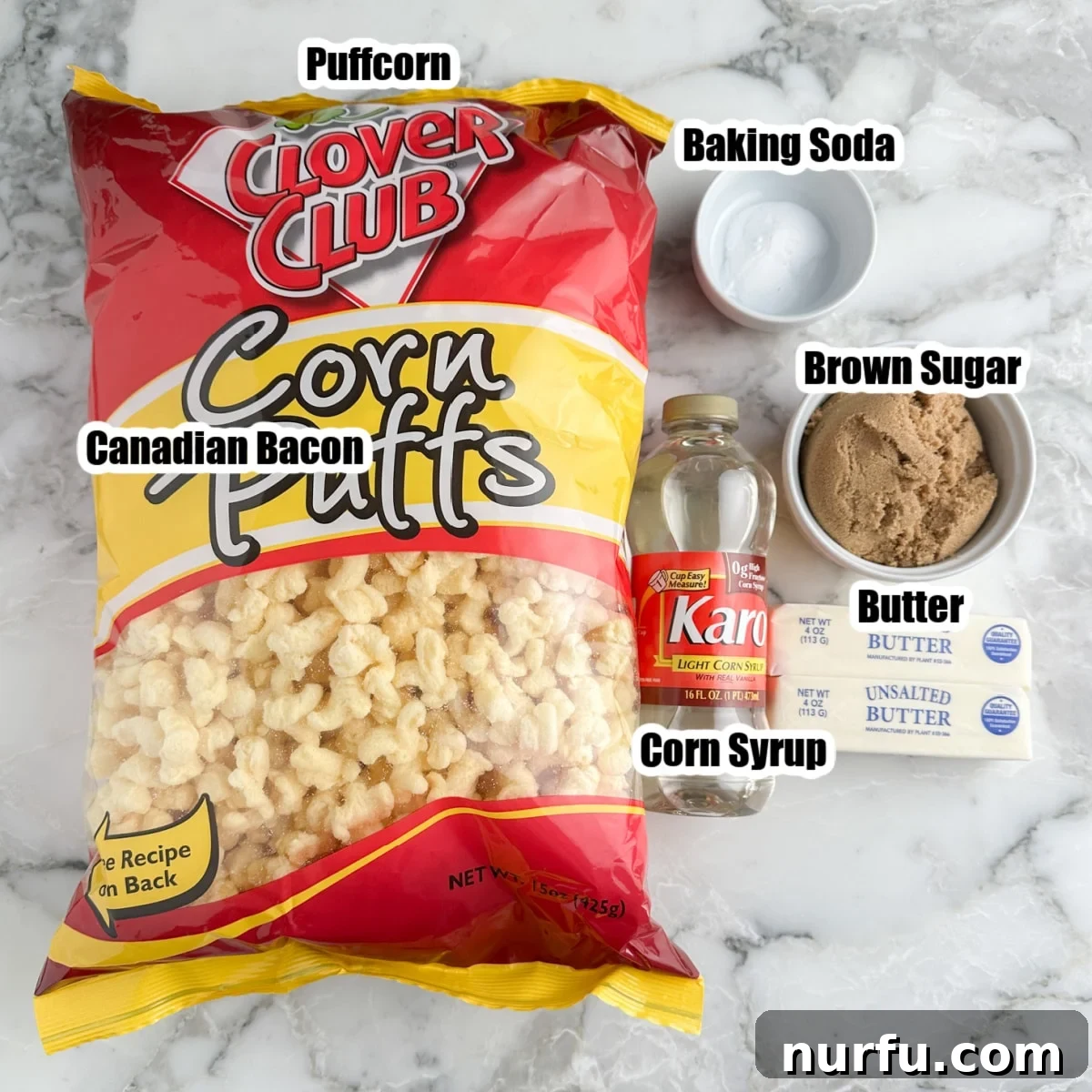 Golden Caramel Clouds 3 A flat lay image showing the key ingredients for caramel puffcorn: a bag of puffcorn, a bowl of brown sugar, a stick of butter, a bottle of corn syrup, and a small dish of baking soda.