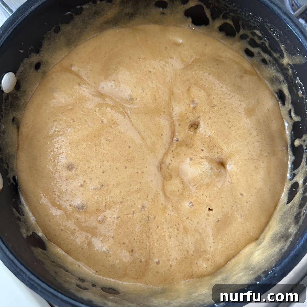 Golden Caramel Clouds 5 Close-up of a saucepan, revealing a rich, bubbling caramel mixture after boiling, prior to adding baking soda.