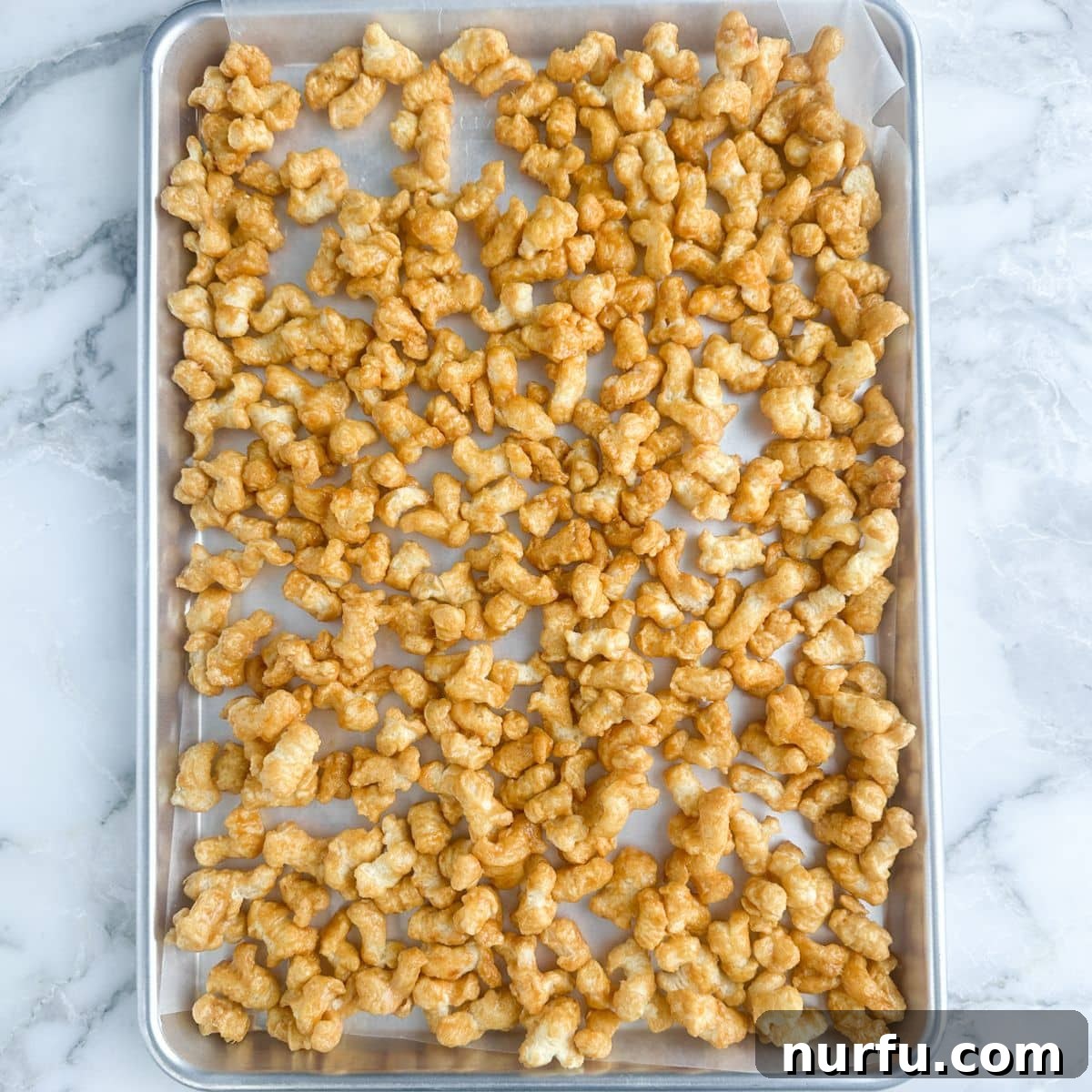 Golden Caramel Clouds 7 A baking pan filled with golden-brown caramel puffcorn, freshly baked and spread out to cool.