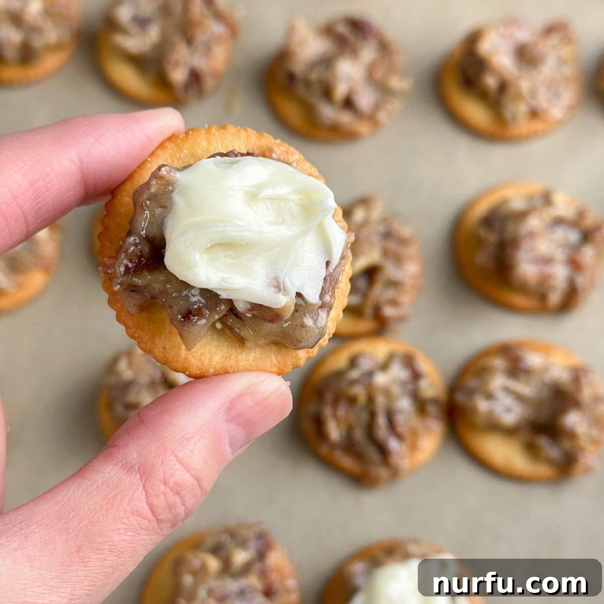 Sweet and Salty Ritz Cracker Delights 8 A single Ritz cracker cookie topped with pecan filling and generous cream cheese frosting, ready to be eaten.