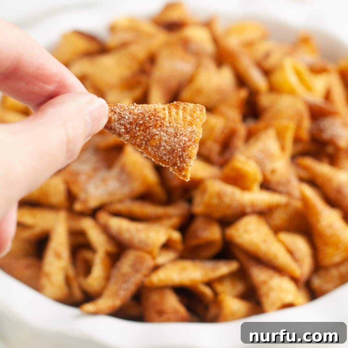 Hand holding cinnamon Bugle chips. 