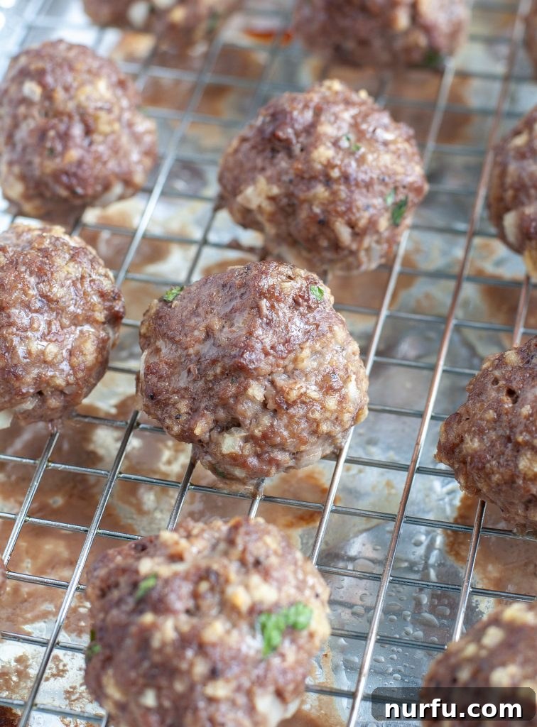 Freshly Baked Meatballs A pile of golden-brown, baked meatballs cooling on a wire rack