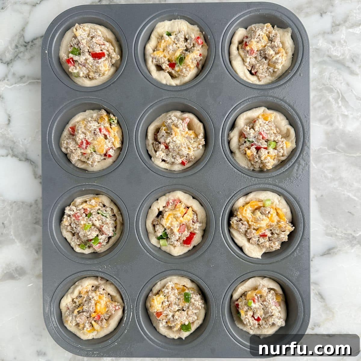 Sausage Cream Cheese Poppers 7 Muffin tin with uncooked cream cheese sausage bites.