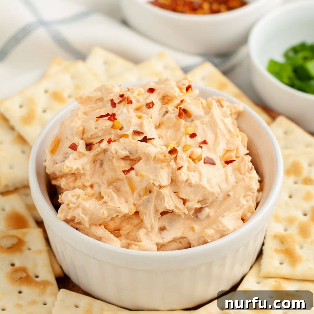 A vibrant bowl of Fire Cracker Dip, generously topped with vivid red pepper flakes, ready to be served and enjoyed.