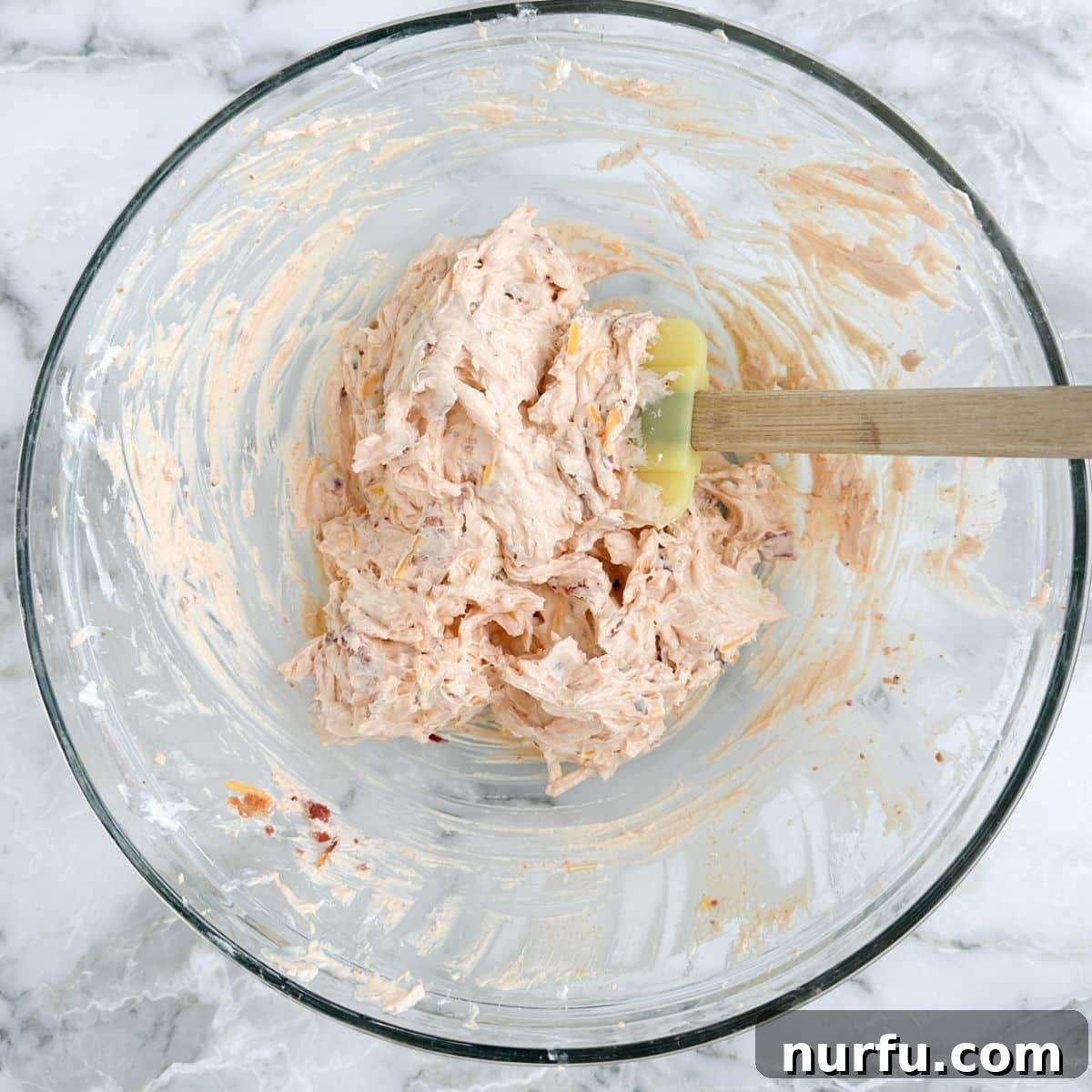 A bowl of freshly made cream cheese dip, perfectly mixed and ready to serve, with a spatula resting alongside.