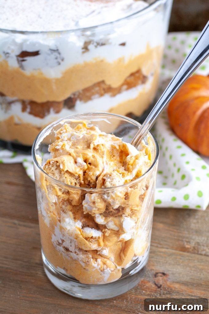 Individual Pumpkin Chai Trifle Serving Pumpkin Chai Trifle served in a glass cup with a spoon, highlighting the delicious layers.