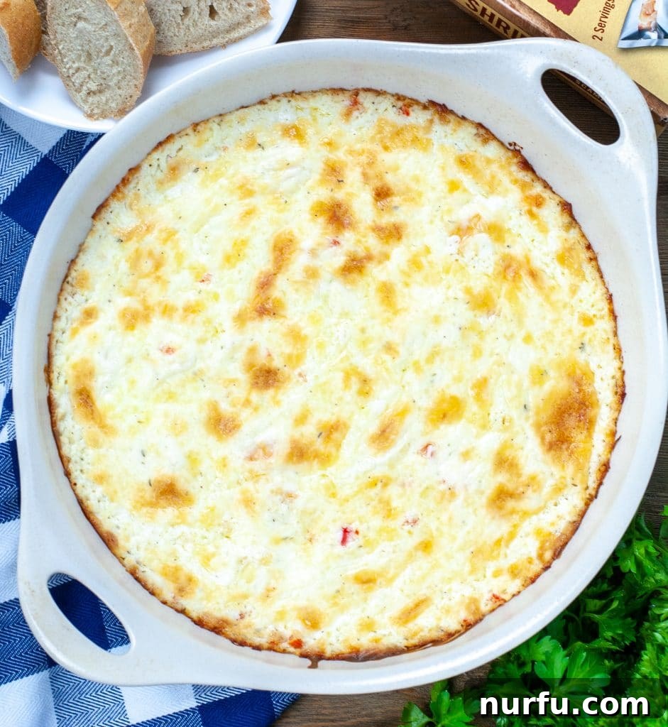 Baking dish filled with shrimp dip. Side plate with bread. 