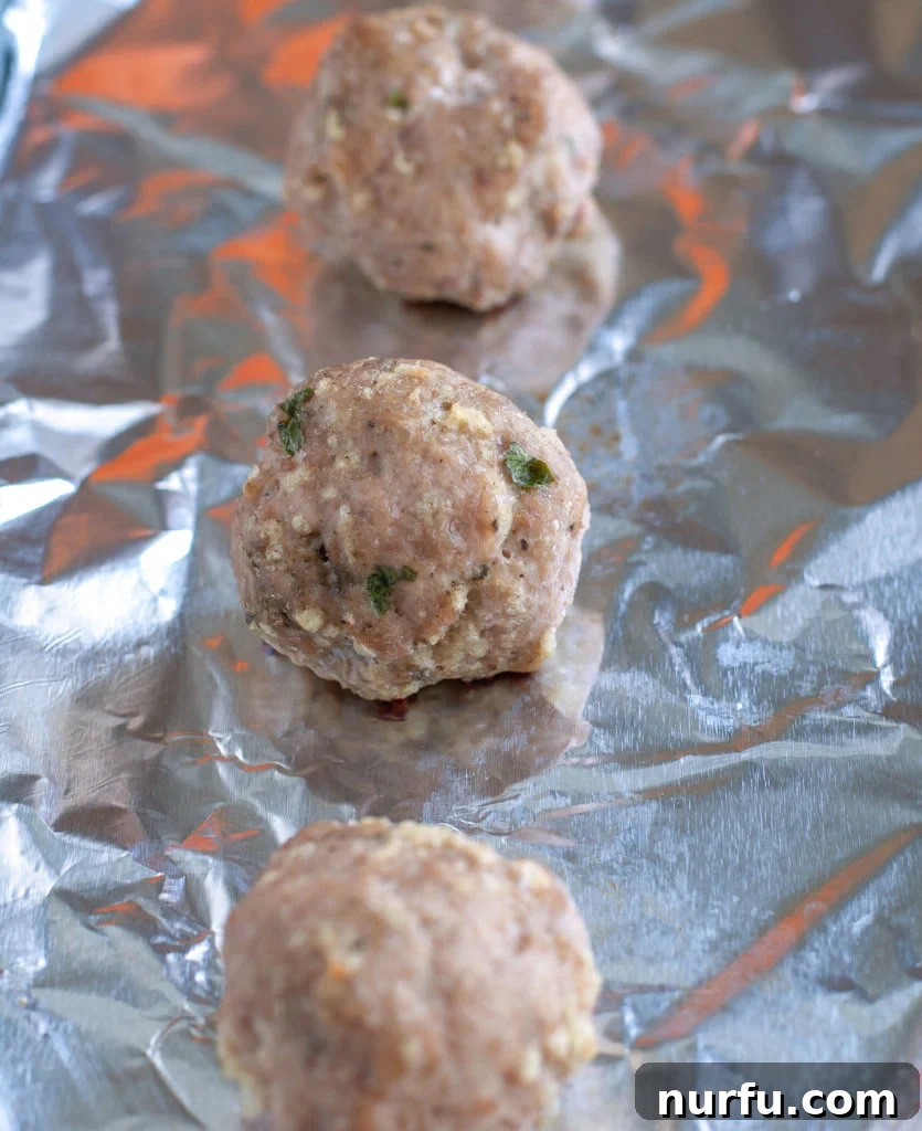 Unbaked turkey meatballs perfectly portioned on a baking sheet Turkey Meatballs on sheet pan