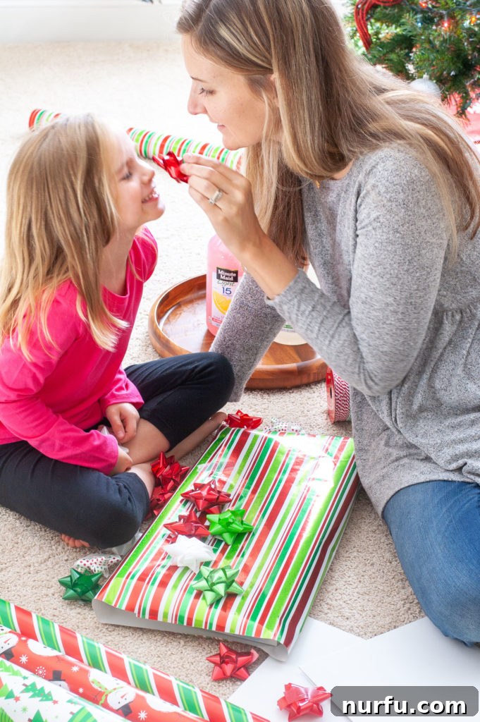 A woman and girl with wrapping paper, sharing a festive moment during the holidays.