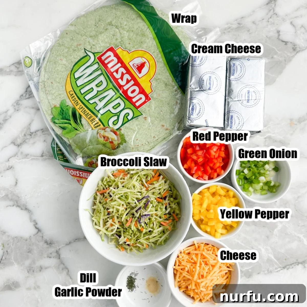 Assorted ingredients for vegetable pinwheels, including spinach tortillas, cream cheese, broccoli slaw, diced peppers, and shredded cheese, laid out on a clean surface.