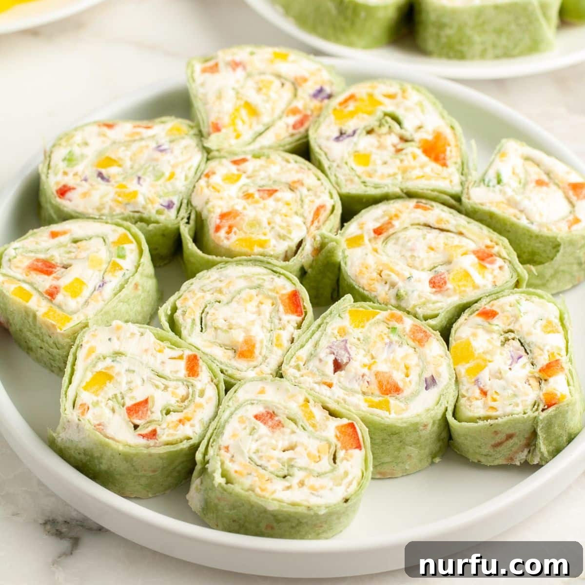 A beautifully arranged plate of colorful vegetable pinwheels, ready to be served as an appetizer.