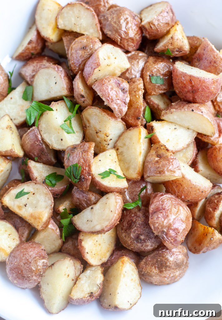 Air Fryer Roasted Potatoes with Herbs A serving bowl of roasted red potatoes garnished with fresh herbs.