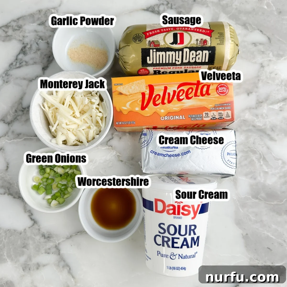Whisker Rage Plunge 3 A selection of Hissy Fit Dip ingredients laid out: cream cheese, Velveeta cheese, shredded Monterey Jack, ground breakfast sausage, sour cream, chopped green onions, garlic powder, and Worcestershire sauce.