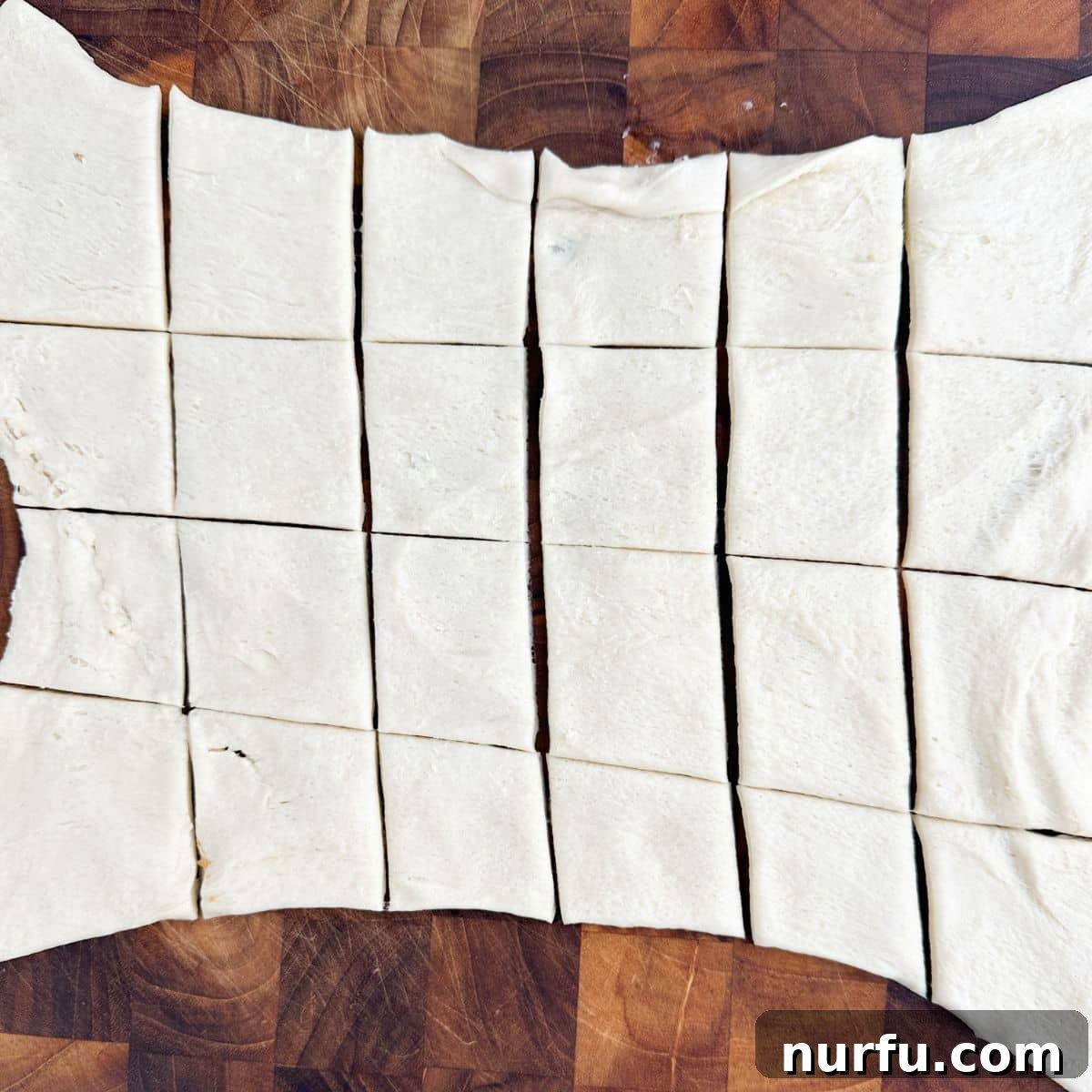 Savory Ham Puffs 4 Crescent roll dough unrolled and neatly cut into small squares, ready for filling.