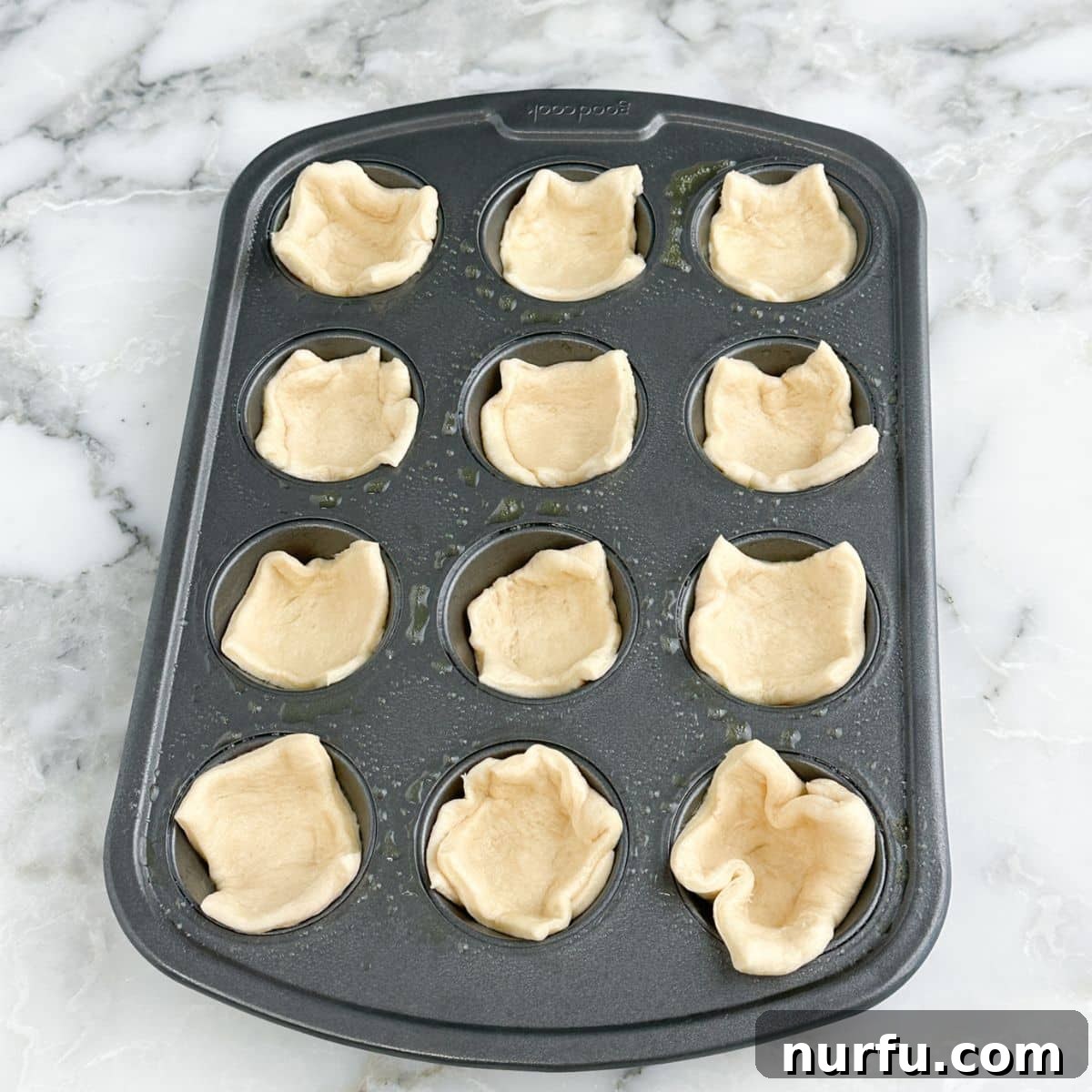 Savory Ham Puffs 5 A mini muffin tin lined with crescent roll dough pieces, forming perfect little cups.