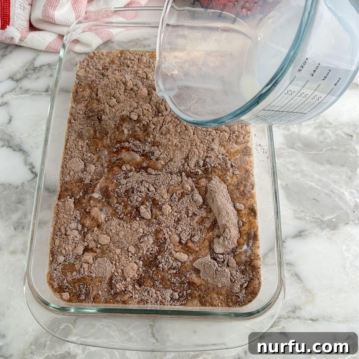 Effortless Chocolate Delight 5 Baking dish with chocolate cake mix and milk being added.