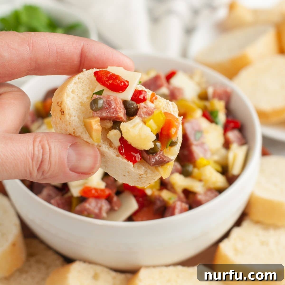 New Orleans Muffuletta Party Dip 6 A slice of toasted baguette generously topped with the flavorful homemade muffuletta dip, showcasing its hearty texture.