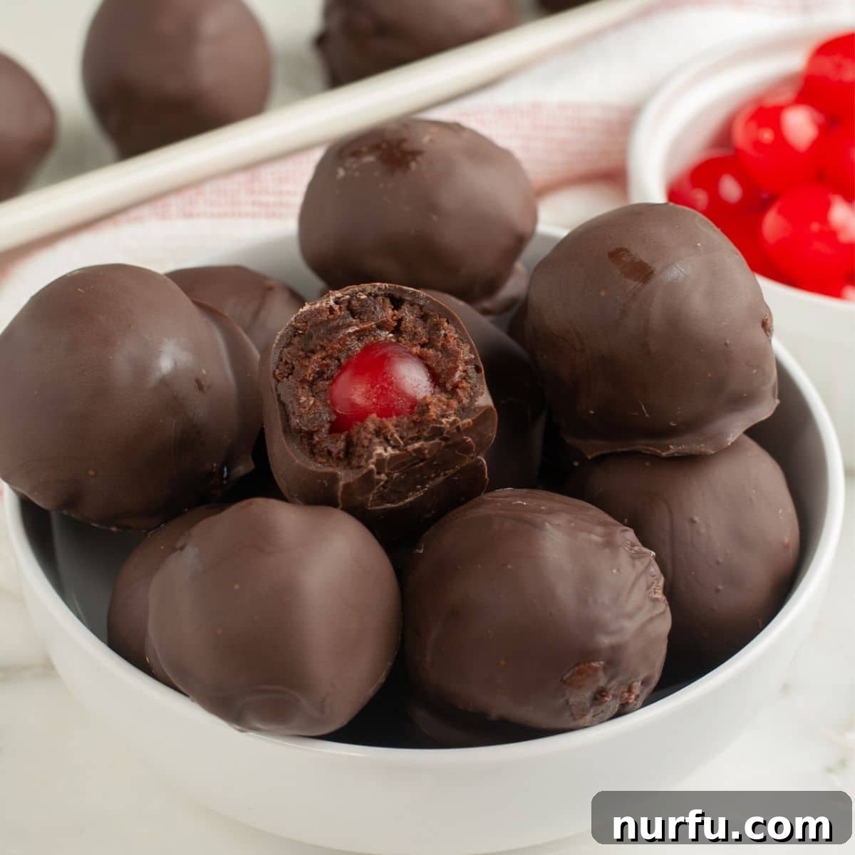 Irresistible Chocolate Cherry Brownie Bites 12 A bowl brimming with finished chocolate-covered cherry brownie bites, each one a perfect sphere with a glossy chocolate shell.