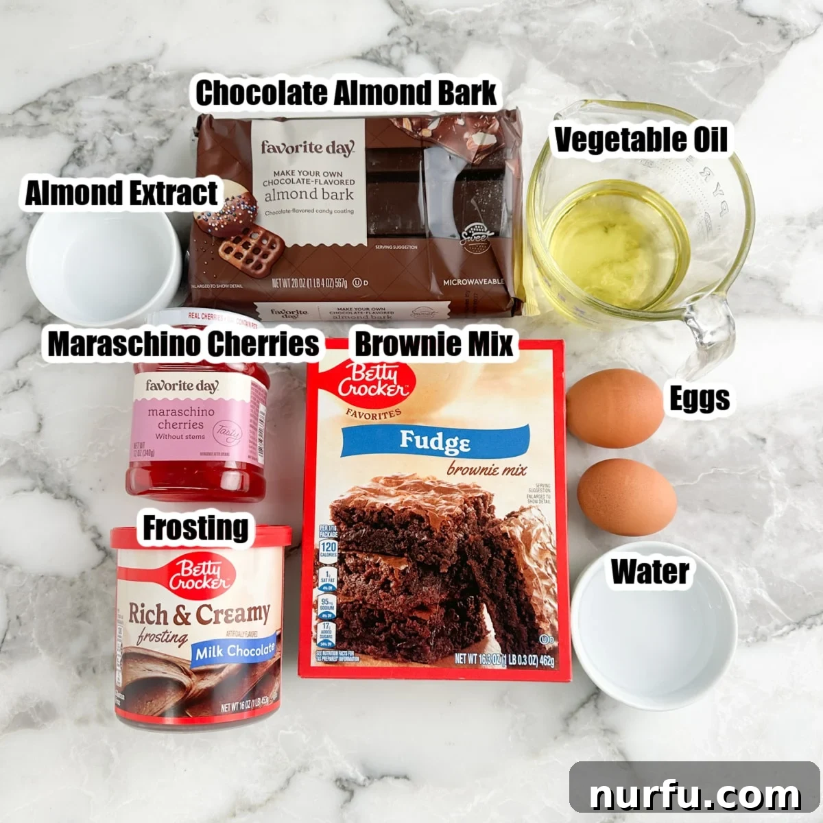 Irresistible Chocolate Cherry Brownie Bites 3 A selection of ingredients laid out, including a box of brownie mix, eggs, vegetable oil, maraschino cherries, a tub of chocolate frosting, and almond bark.