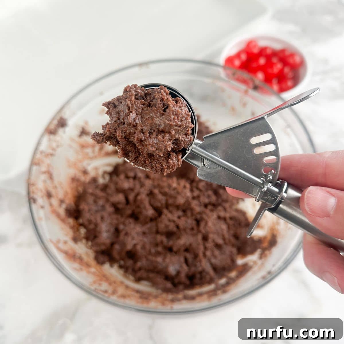 Irresistible Chocolate Cherry Brownie Bites 6 A cookie dough scoop filled with the brownie and frosting mixture, showing its soft consistency.