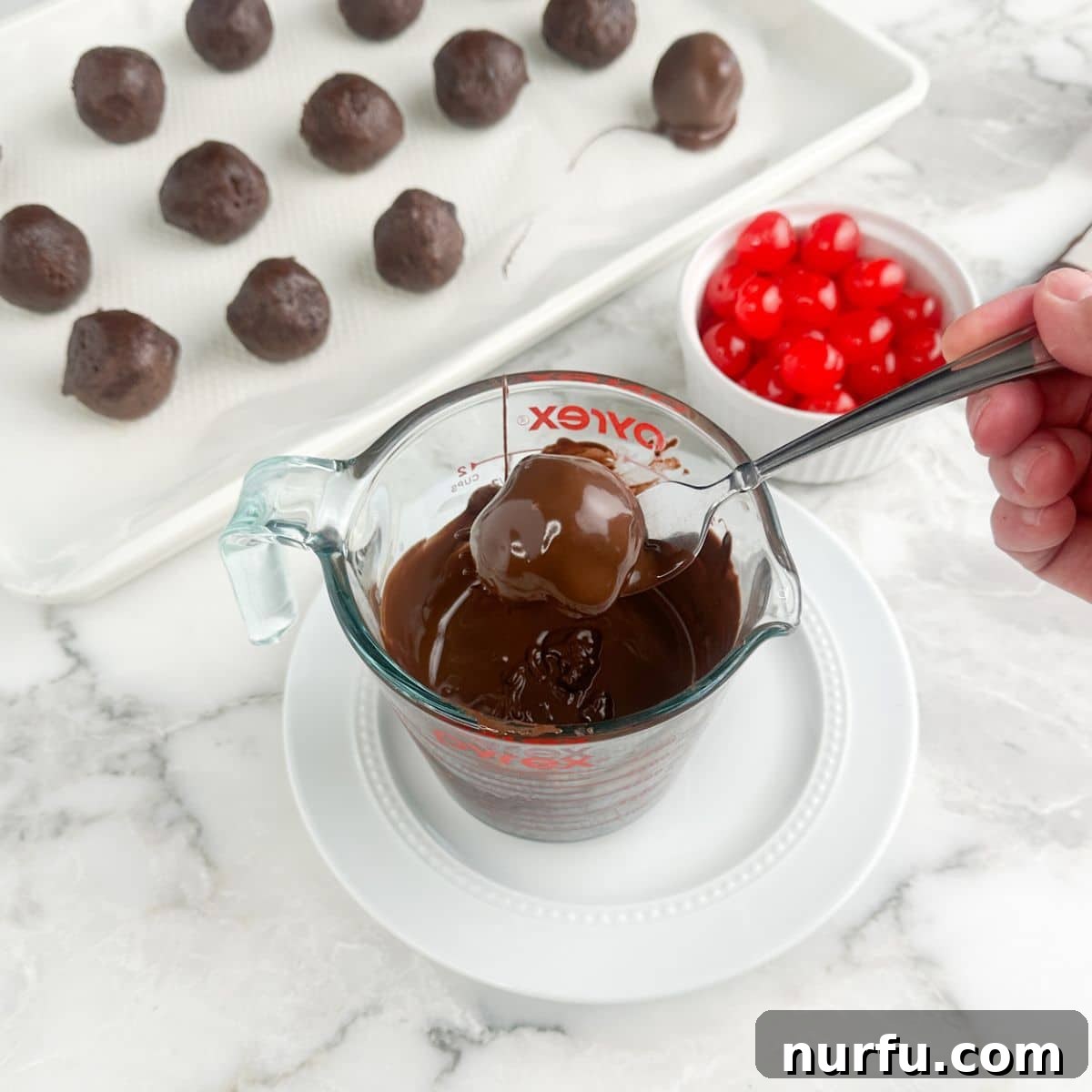 Irresistible Chocolate Cherry Brownie Bites 10 A brownie bite being gently lowered into a bowl of perfectly melted chocolate, for a smooth coating.