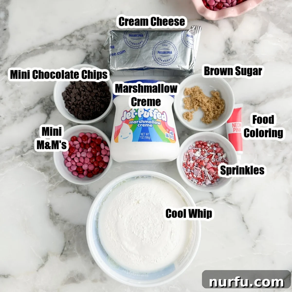 Pink Party Dip 3 Assortment of ingredients laid out on a surface: cream cheese, a tub of Cool Whip, a bowl of brown sugar, colorful sprinkles, mini chocolate chips, and marshmallow creme, essential for making the Pink Booty Dip.