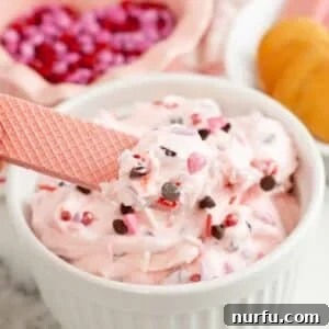 Bowl of pink booty dip with a pink cookie dipping in.