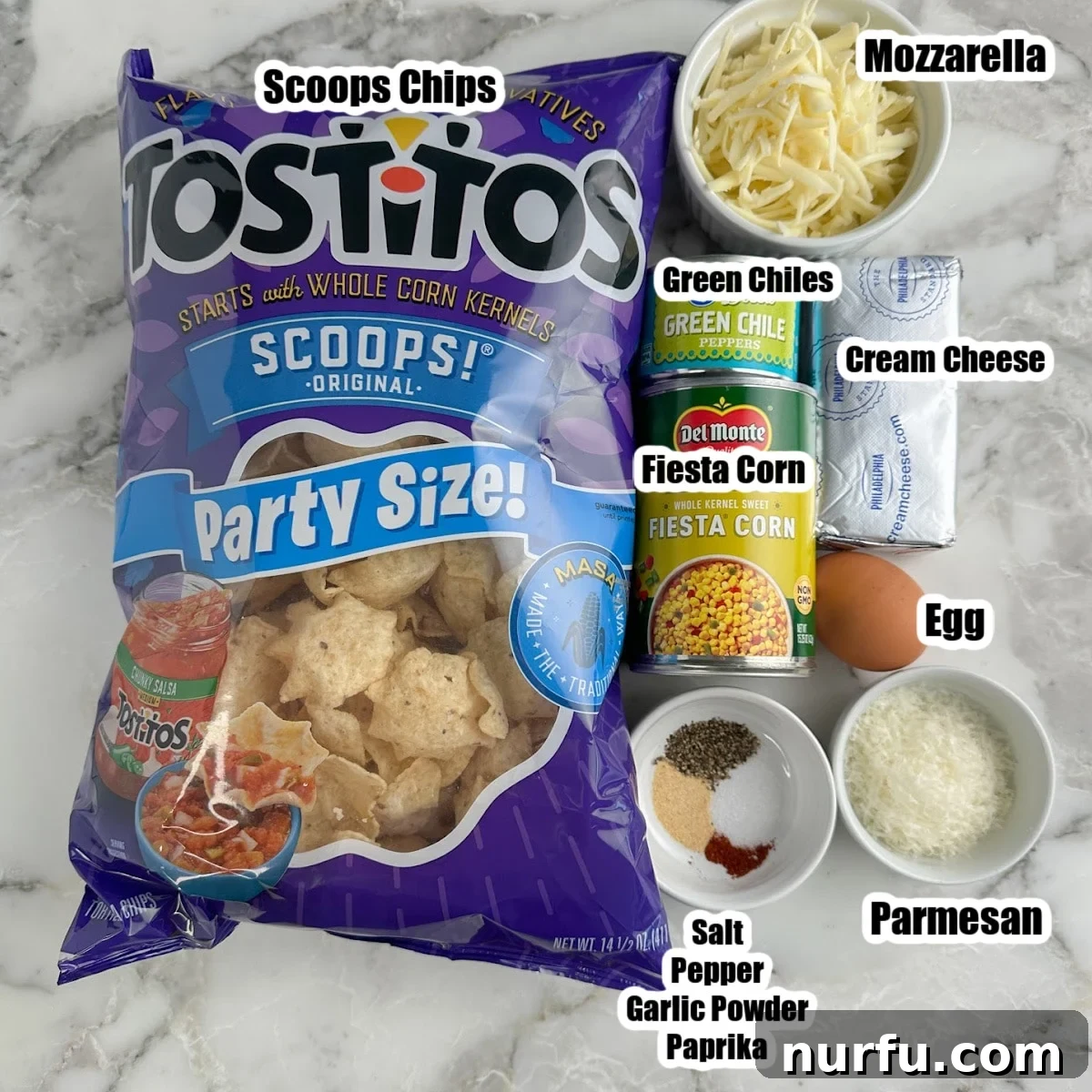 Hawkeye Hootenanny Bites 3 Bag of Tostitos Scoops chips, bowls of shredded cheese, cream cheese, fiesta corn, green chiles, and seasonings laid out on a table.