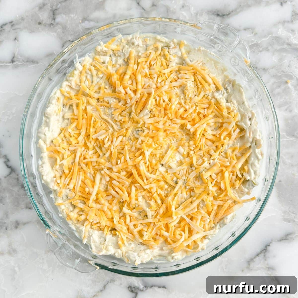 Zesty Green Chile Dip 6 Pie dish with cream cheese dip topped with shredded cheese.