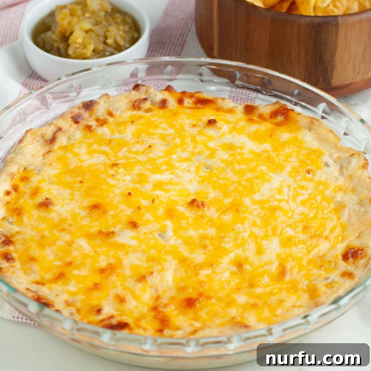 Zesty Green Chile Dip 8 Close up of green chile cheese dip in a baking dish with a chip scooping some out.