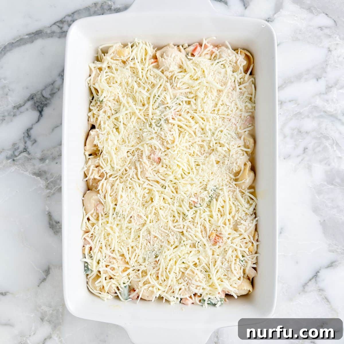 Casserole dish with unbaked chicken tortellini casserole. 
