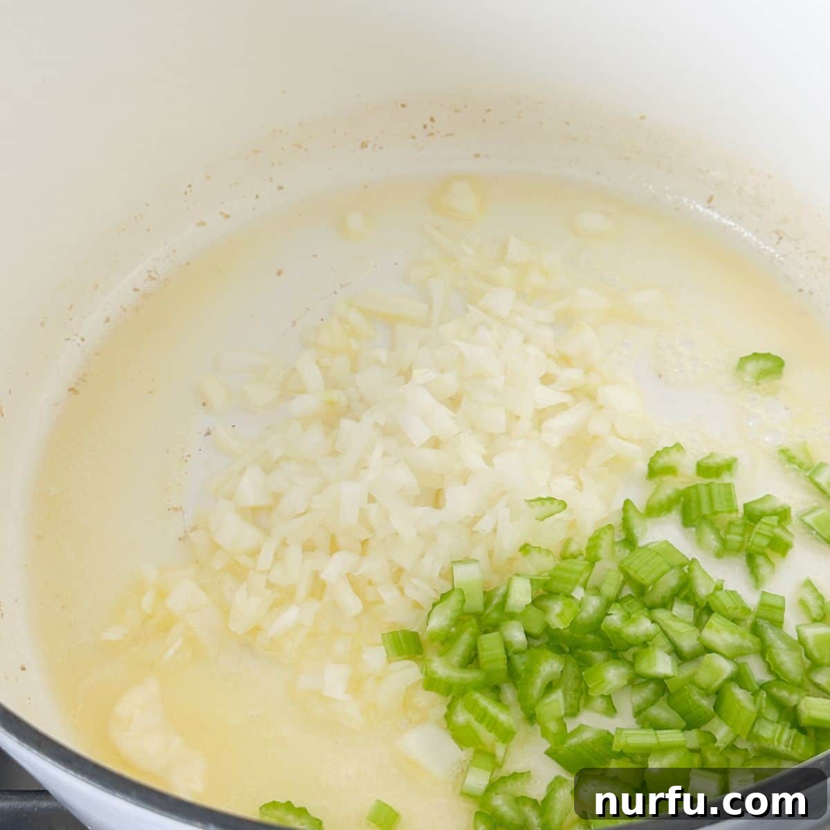 Hearty Chicken Pot Pie Pasta 4 A large pot on a stovetop containing melted butter with diced onion and celery simmering until softened, ready for the next step of sauce preparation.