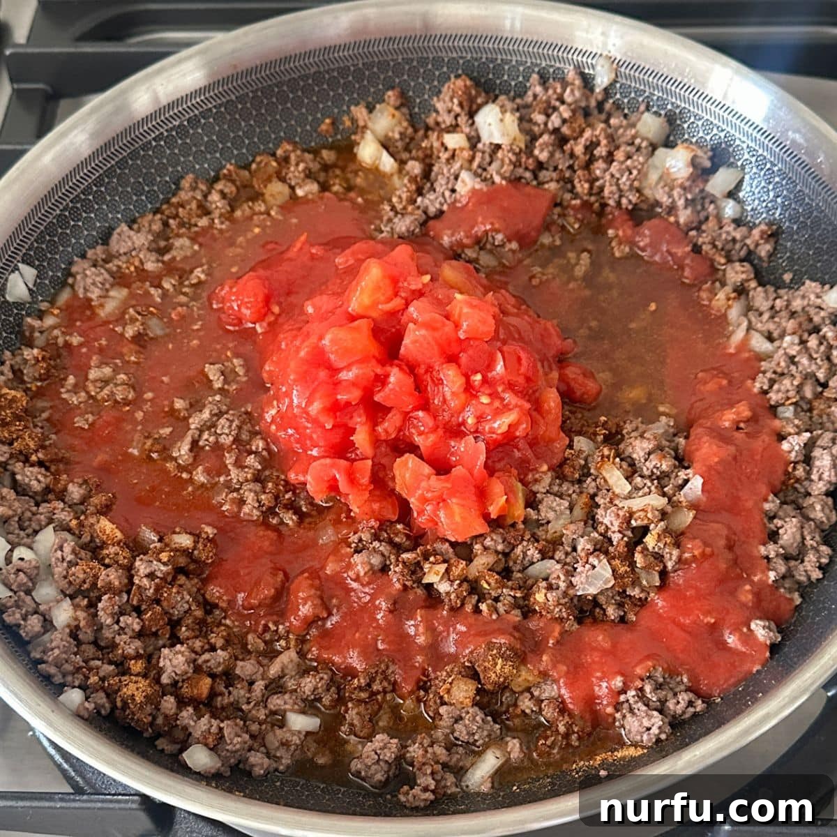 Fiesta Tortellini 6 A skillet filled with ground beef, tomato sauce, and diced tomatoes with green chilies, simmering gently.