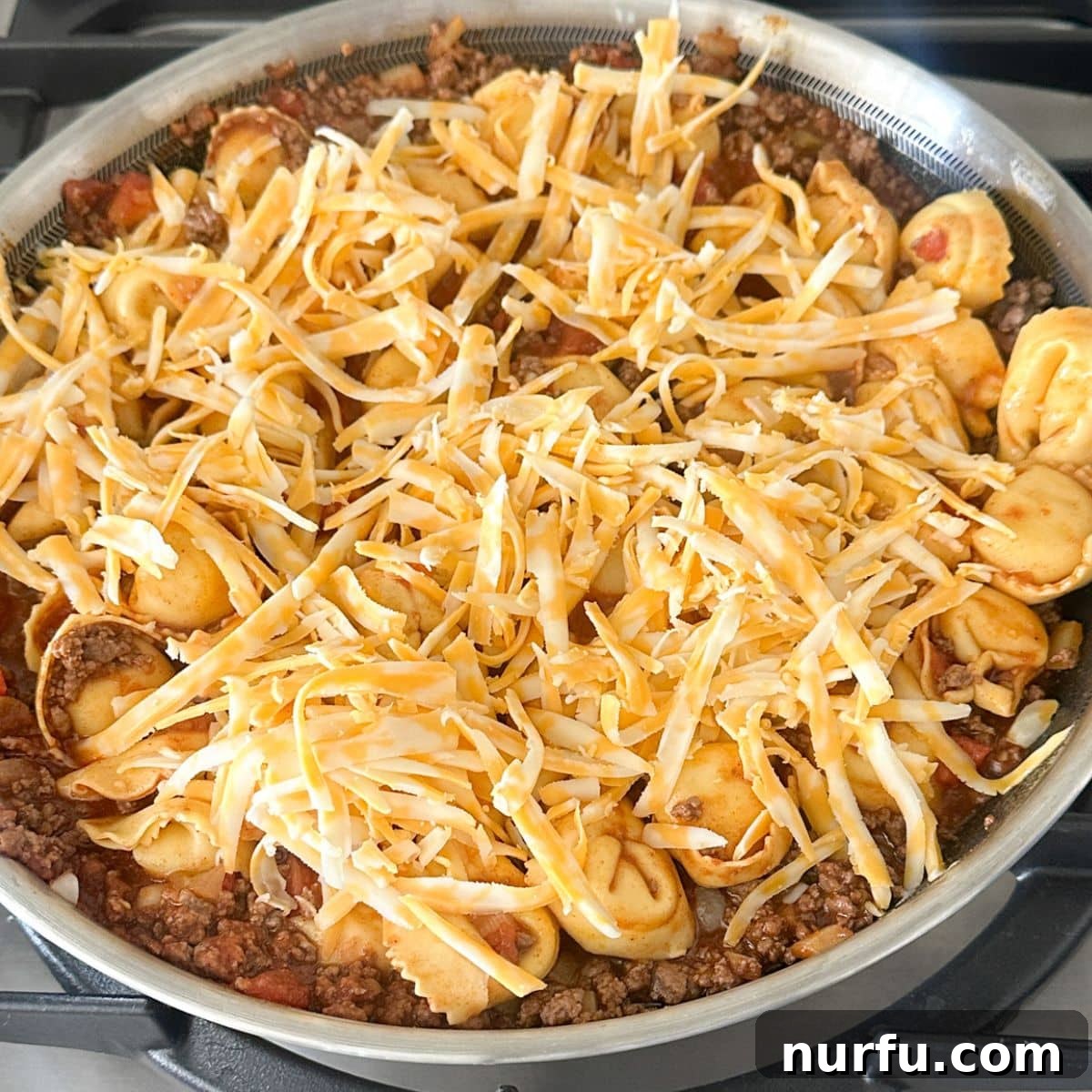 Fiesta Tortellini 8 A skillet of cheesy taco tortellini, freshly topped with shredded cheese and ready to serve.