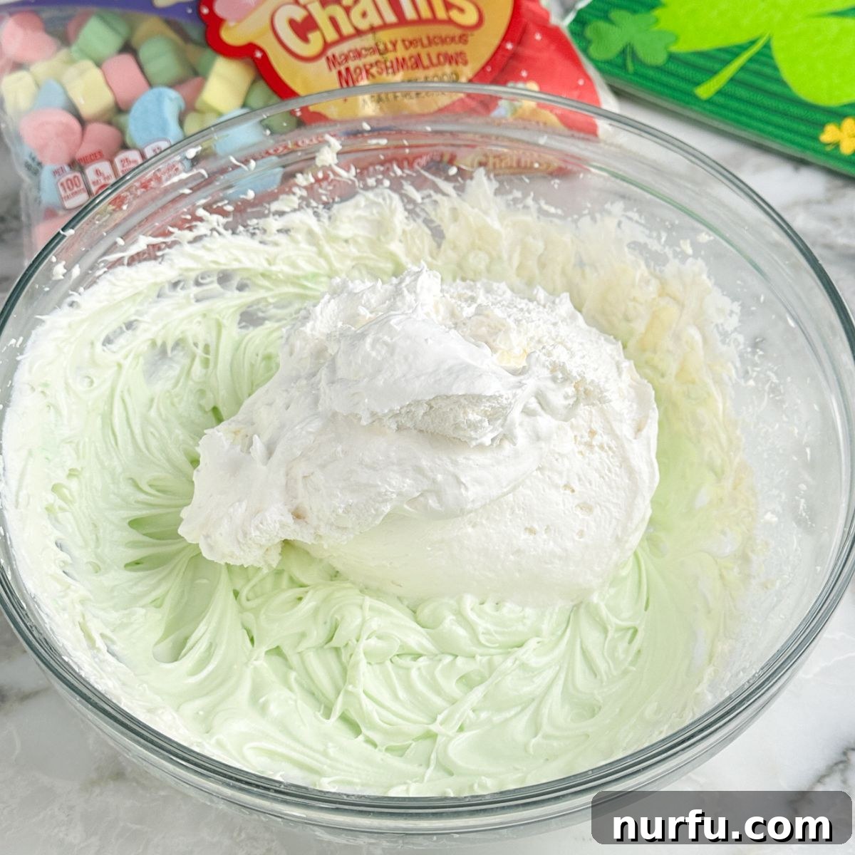 Pot of Gold Dessert Dip 5 Bowl of green beaten cream cheese and Cool Whip, showing the vibrant color of the dessert dip.