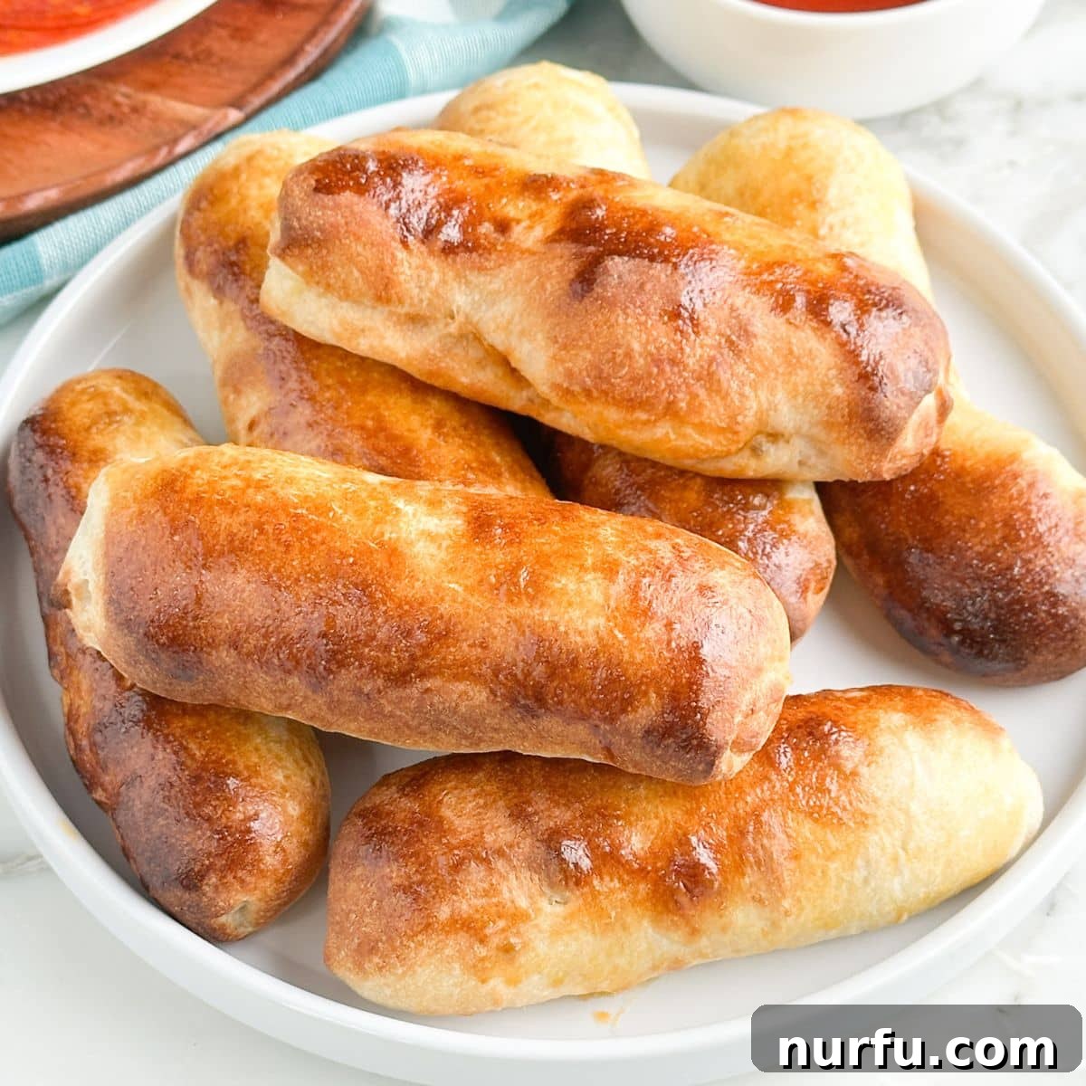 Cheesy Pepperoni Rolls 2 A close-up shot of freshly baked homemade pepperoni rolls, golden brown and filled with cheese and pepperoni, served on a rustic plate.