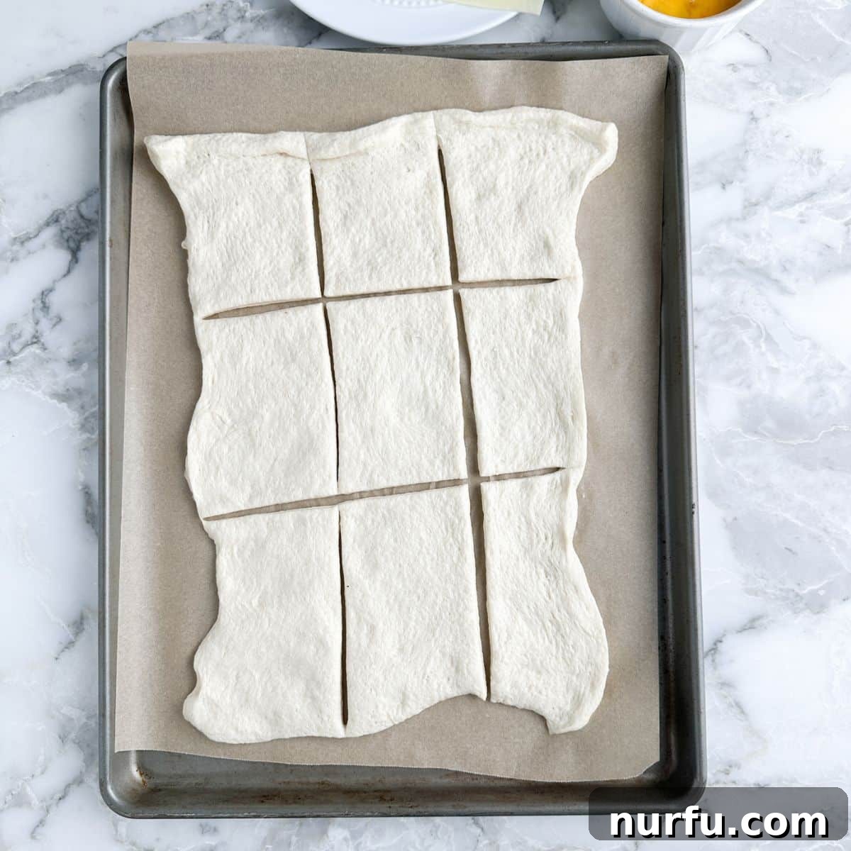 Cheesy Pepperoni Rolls 4 A baking pan with unrolled bread dough divided into nine rectangular sections, ready for filling.