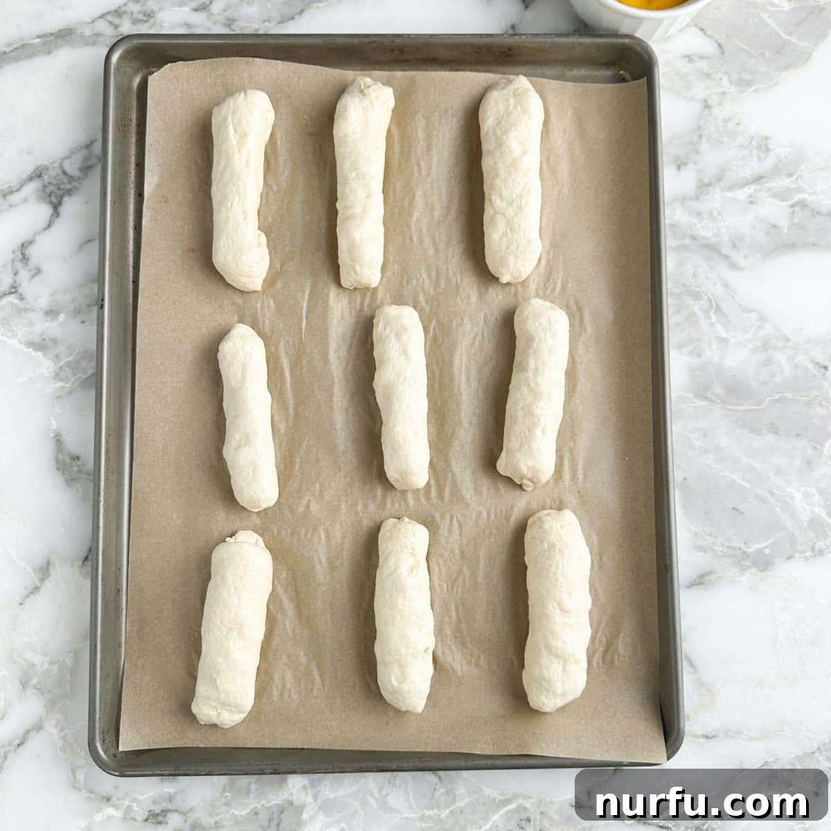 Cheesy Pepperoni Rolls 6 A baking pan displaying uncooked pepperoni rolls neatly arranged, before the application of egg wash.