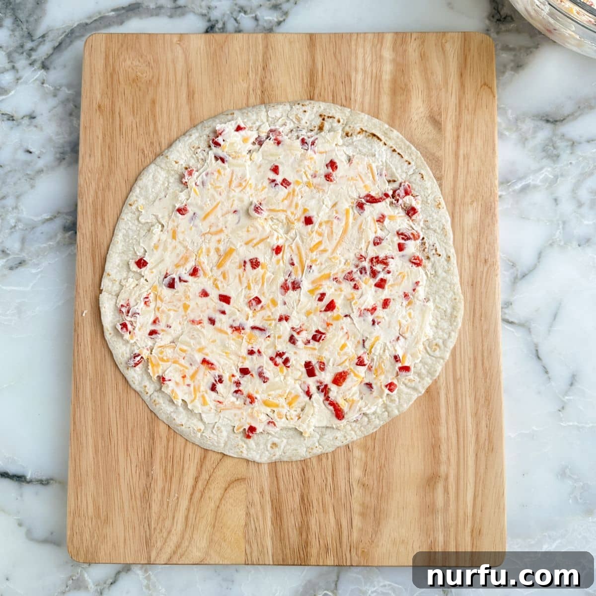 A flour tortilla generously topped with the pimento cheese mixture, spread almost to the edges.