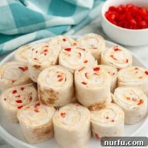 A beautifully arranged plate of golden-hued pimento cheese pinwheels, ready to be served as an appetizer.