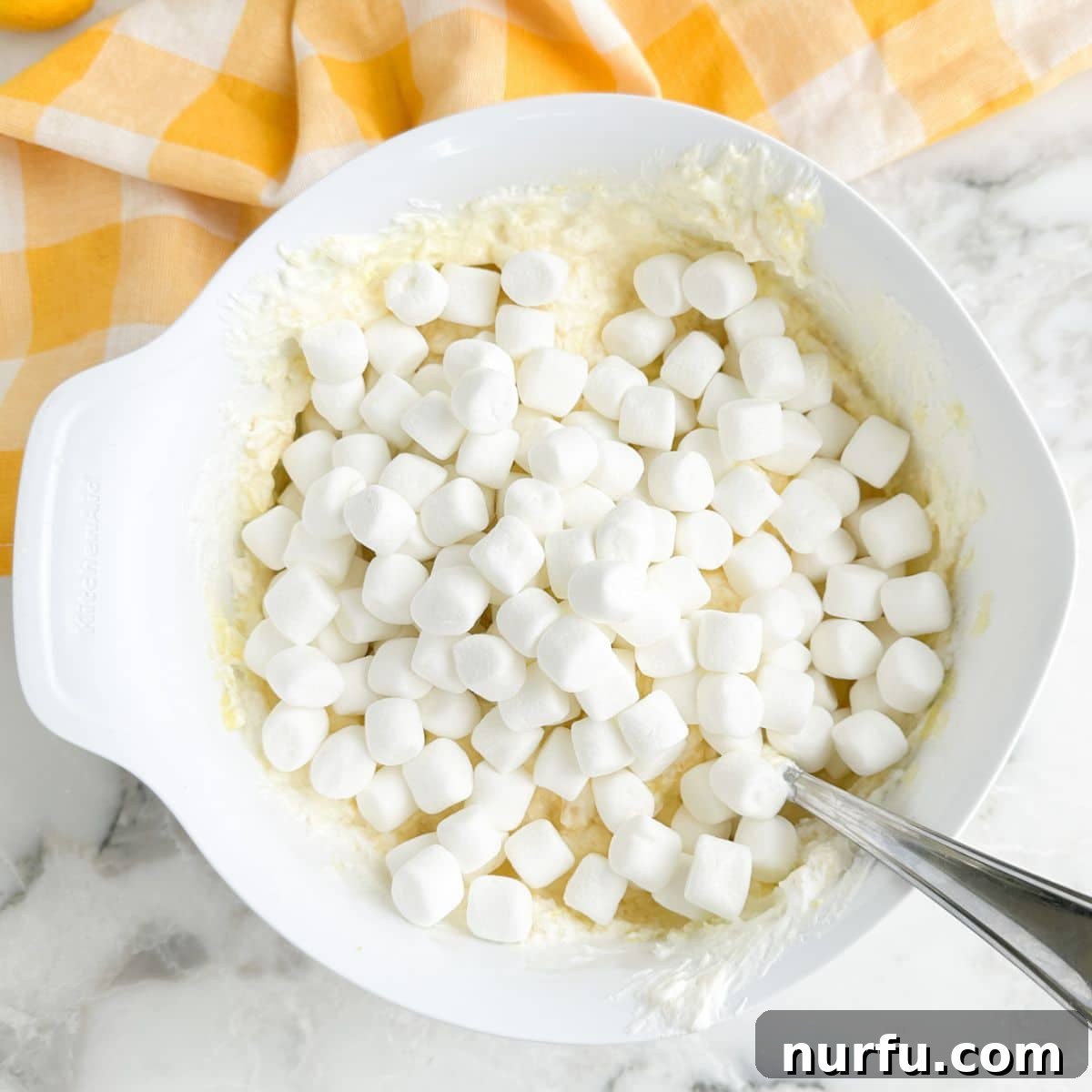 A bowl containing the lemon-pineapple mixture with mini marshmallows folded in, creating a delightful Lemon Marshmallow Fluff.