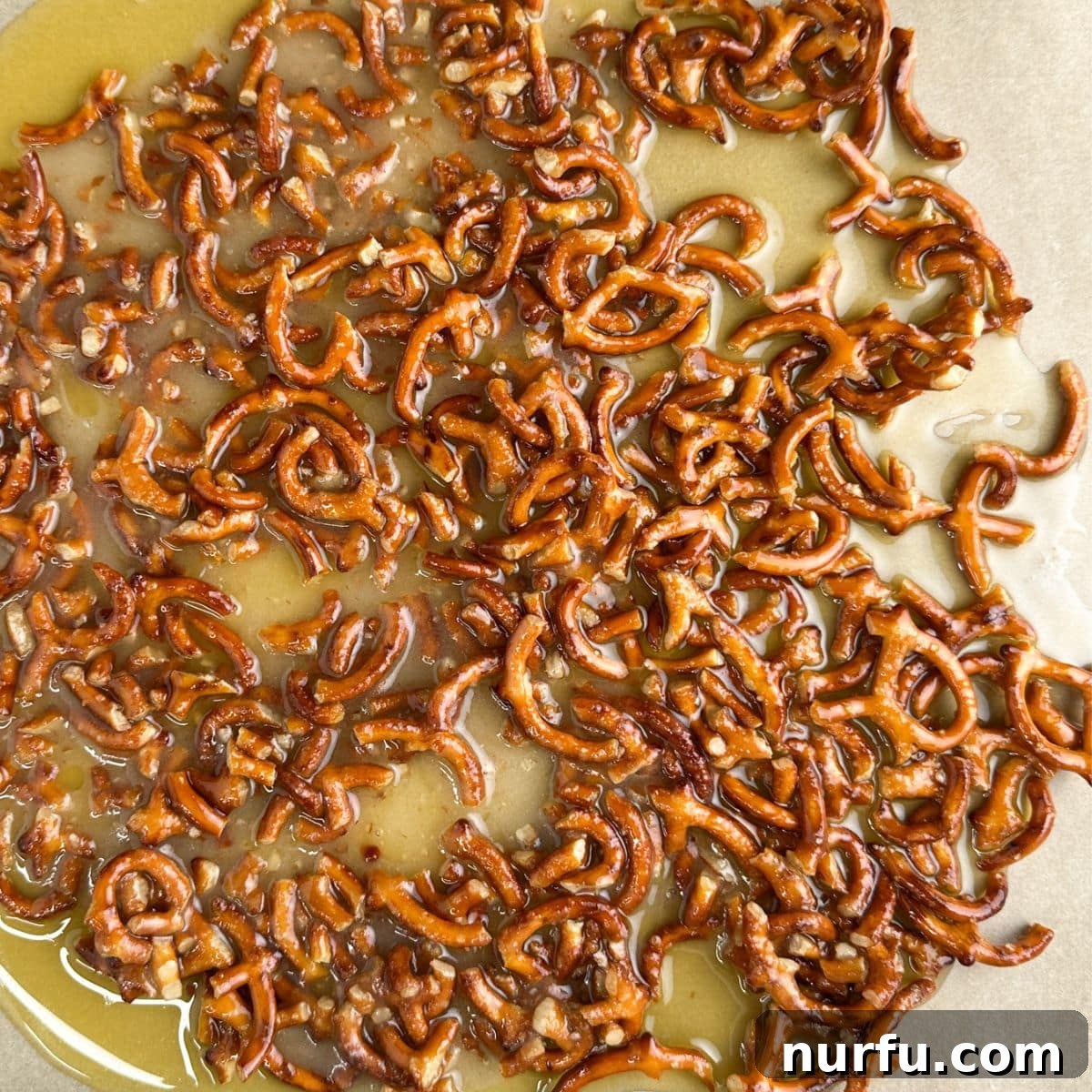 Sweet and Salty Pineapple Swirl 6 Broken pretzels mixed with melted butter spread on a baking sheet, ready for the oven.