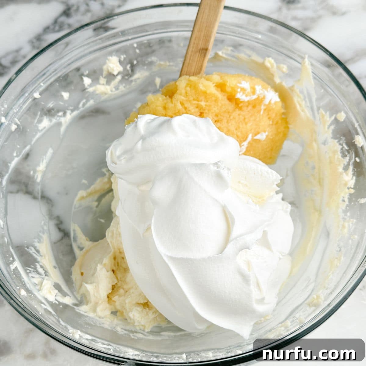 Sweet and Salty Pineapple Swirl 7 Bowl of whipped topping and crushed pineapples being gently combined.